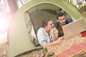 happy couple using laptop in tent